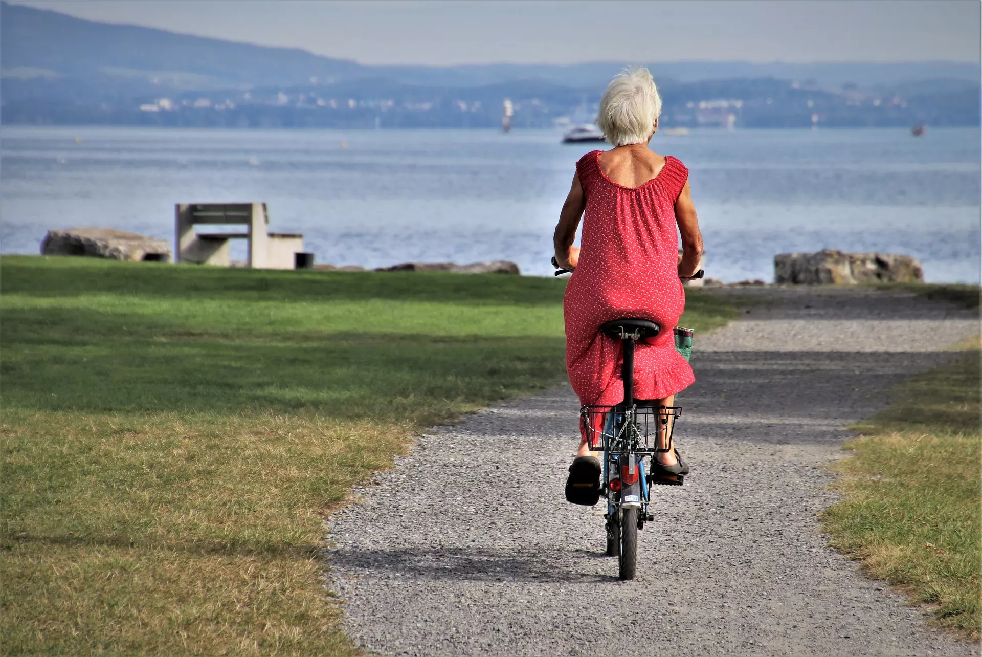 An old woman biking towards the sea